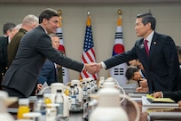 Two men shake hands over a large table.