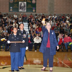 Dr. Isabell Clayton (right), Cole High School principal, holds the Purple Heart medal of Lt. Col. Robert G. Cole for parents, teachers, students and World War II veterans who were present to see at a Veterans Day observance at the Cole High School gymnasium Nov. 8. The Purple Heart medal, which was awarded to Cole posthumously 75 years ago, made its way to the school named after him because of the efforts of Lisa Ludwig, a Long Island, New York resident who found and purchased the medal at a gun show and donated it to the school.