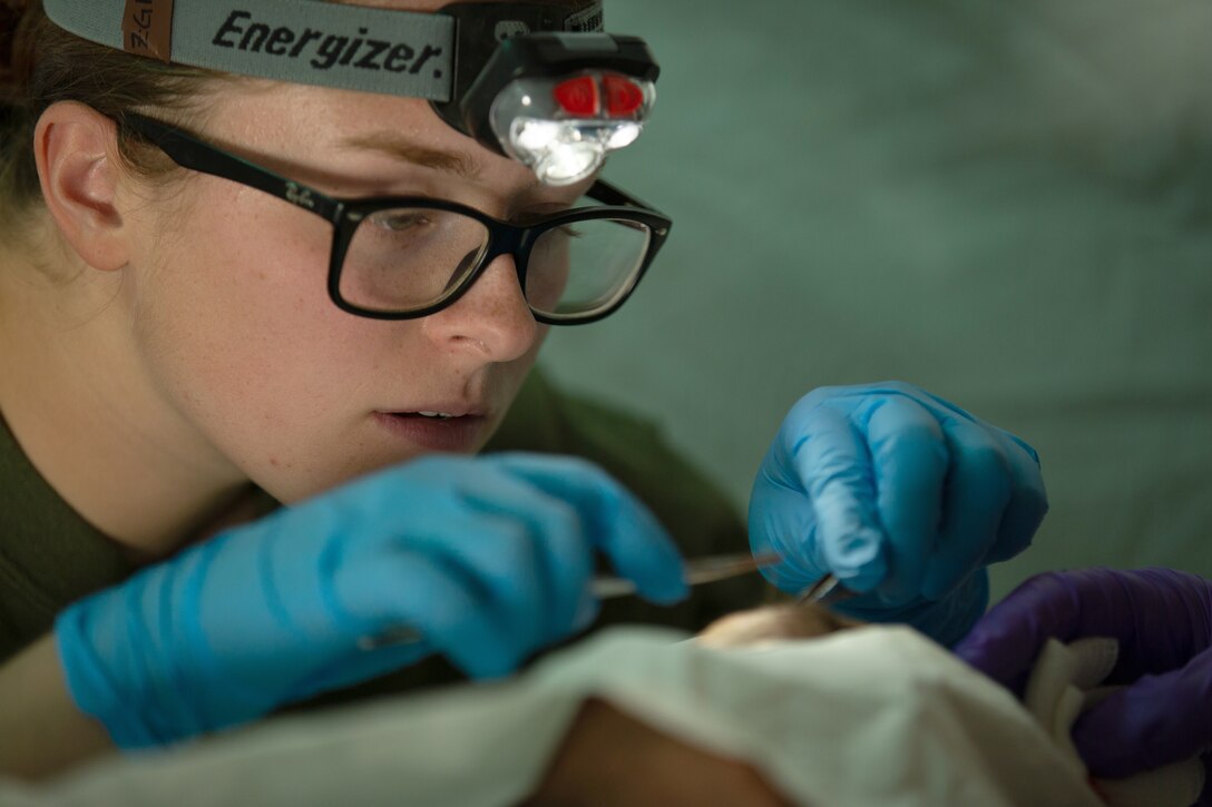 A service member focuses as she performs a medical operation.