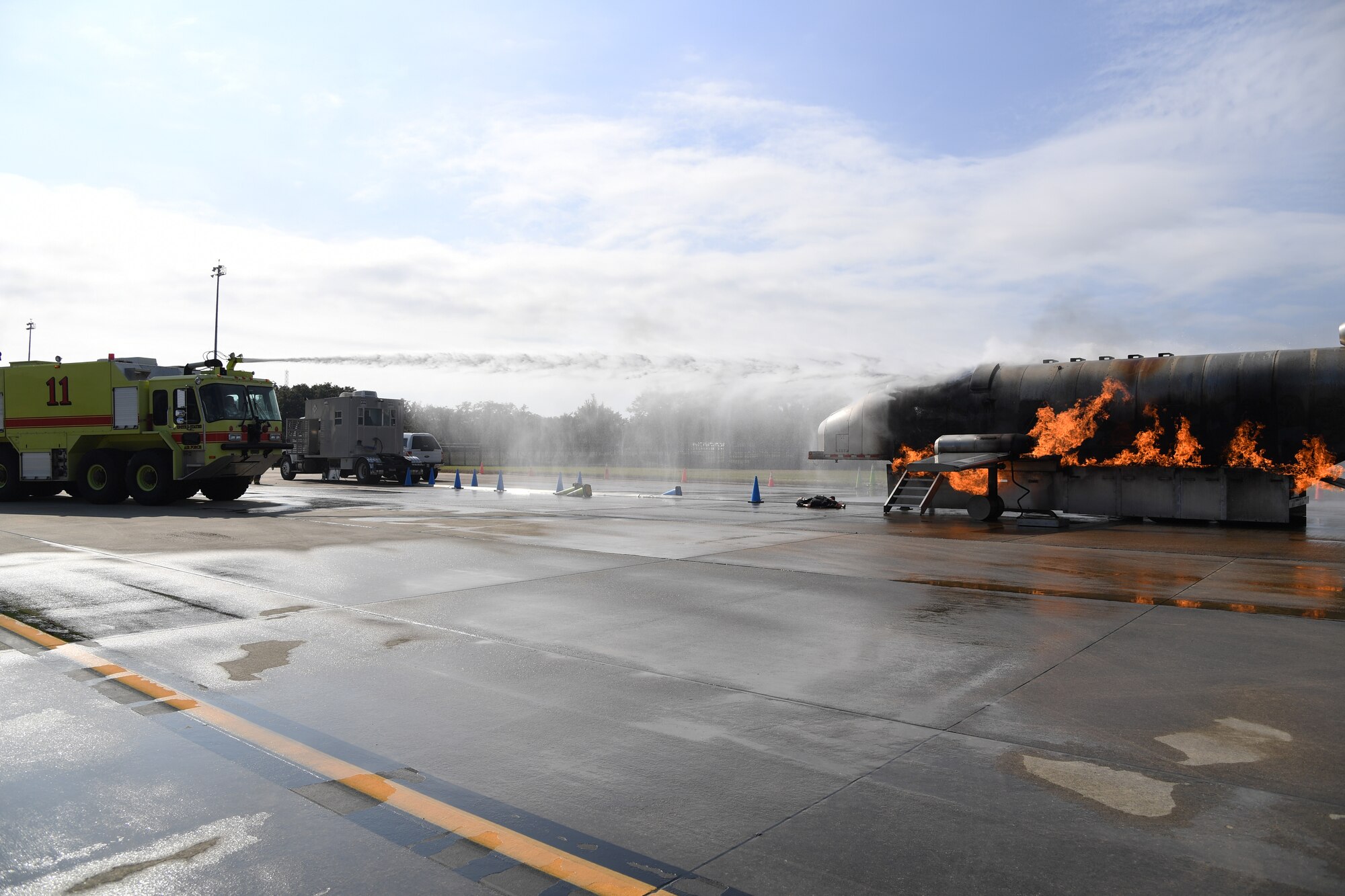 Keesler firefighters operate a fire truck to extinguish a fire on a mock C-123 training device during an aircraft rescue fire fighting training exercise at Keesler Air Force Base, Mississippi, Nov. 6, 2019. The five-day joint agency training allowed the Keesler Fire Department and the Gulfport Combat Readiness Training Center Fire Department to meet the semi-annual training requirement to practice aircraft rescue and live fire training evolutions. (U.S. Air Force photo by Kemberly Groue)
