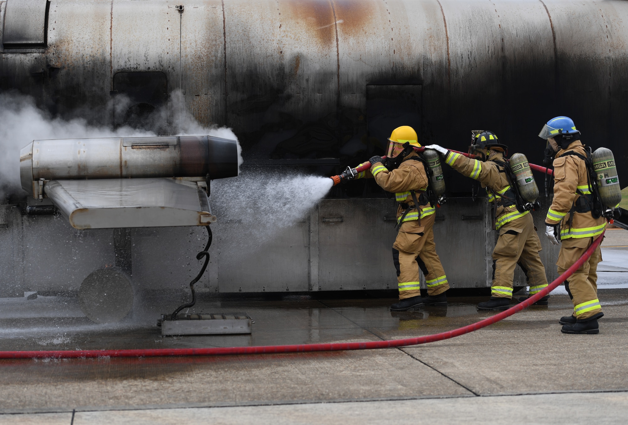 U.S. Air Force Airman Mason Songy, 209th Civil Engineer Squadron firefighter, Gulfport Combat Readiness Training Center Fire Department, Mississippi, and James Pettus and Guy Chadwick, 81st Infrastructure Division firefighters, use a hand-held hose to extinguish a fire on a mock C-123 training device during an aircraft rescue fire fighting training exercise at Keesler Air Force Base, Mississippi, Nov. 8, 2019. The five-day joint agency training allowed the Keesler Fire Department and the Gulfport Combat Readiness Training Center Fire Department to meet the semi-annual training requirement to practice aircraft rescue and live fire training evolutions. (U.S. Air Force photo by Kemberly Groue)