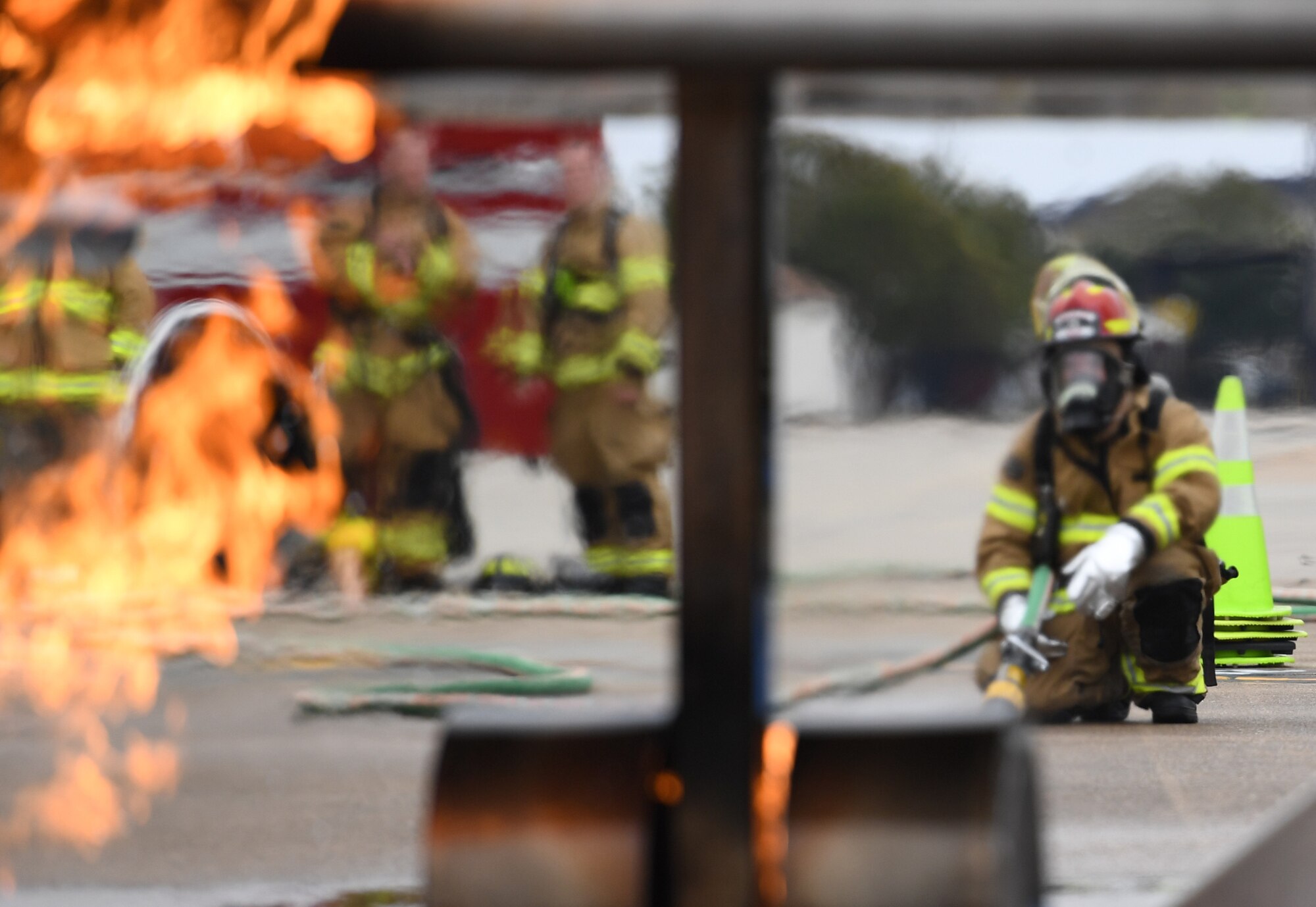 Keesler firefighters use a hand-held hose to extinguish a fire on a mock C-123 training device during an aircraft rescue fire fighting training exercise at Keesler Air Force Base, Mississippi, Nov. 8, 2019. The five-day joint agency training allowed the Keesler Fire Department and the Gulfport Combat Readiness Training Center Fire Department to meet the semi-annual training requirement to practice aircraft rescue and live fire training evolutions. (U.S. Air Force photo by Kemberly Groue)