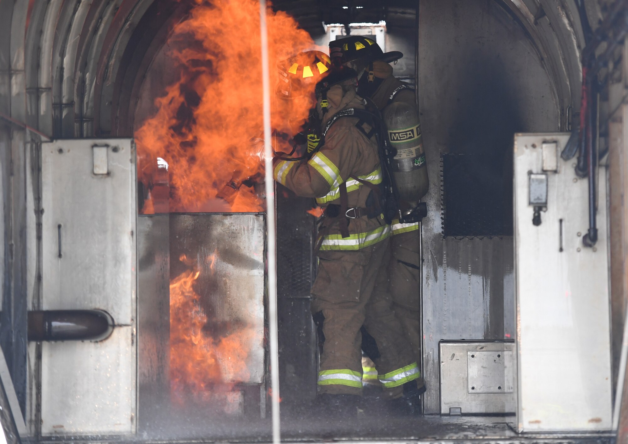 Cole Ballard and Seth Corn, 81st Infrastructure Division firefighters, use a hand-held hose to extinguish a fire inside a mock C-123 training device during an aircraft rescue fire fighting training exercise at Keesler Air Force Base, Mississippi, Nov. 8, 2019. The five-day joint agency training allowed the Keesler Fire Department and the Gulfport Combat Readiness Training Center Fire Department to meet the semi-annual training requirement to practice aircraft rescue and live fire training evolutions. (U.S. Air Force photo by Kemberly Groue)
