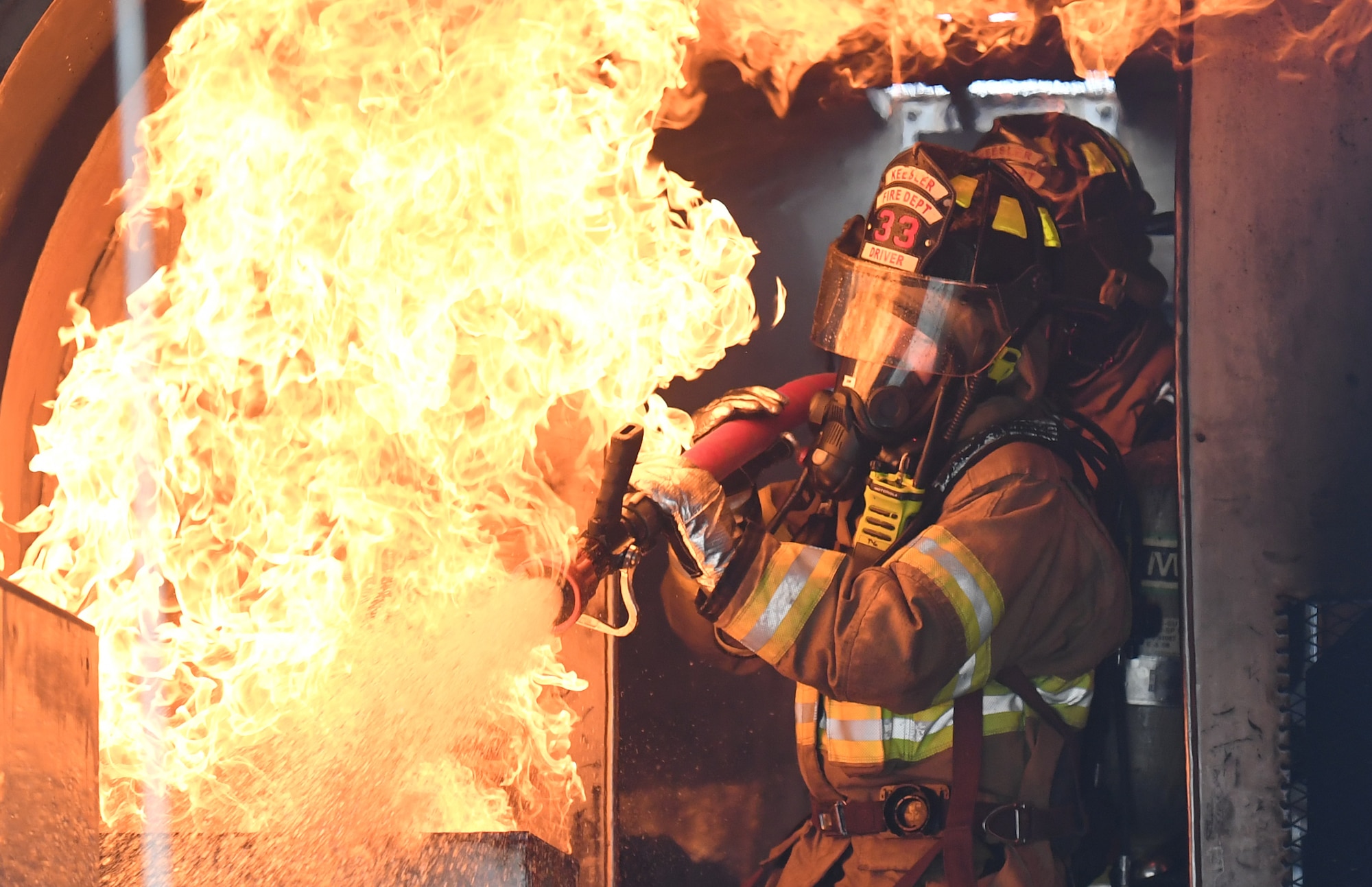 Cole Ballard and Seth Corn, 81st Infrastructure Division firefighters, use a hand-held hose to extinguish a fire inside a mock C-123 training device during an aircraft rescue fire fighting training exercise at Keesler Air Force Base, Mississippi, Nov. 8, 2019. The five-day joint agency training allowed the Keesler Fire Department and the Gulfport Combat Readiness Training Center Fire Department to meet the semi-annual training requirement to practice aircraft rescue and live fire training evolutions. (U.S. Air Force photo by Kemberly Groue)