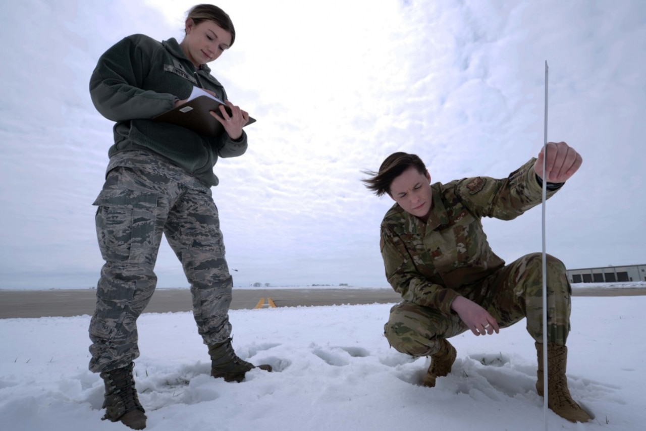 Two people measure snow.