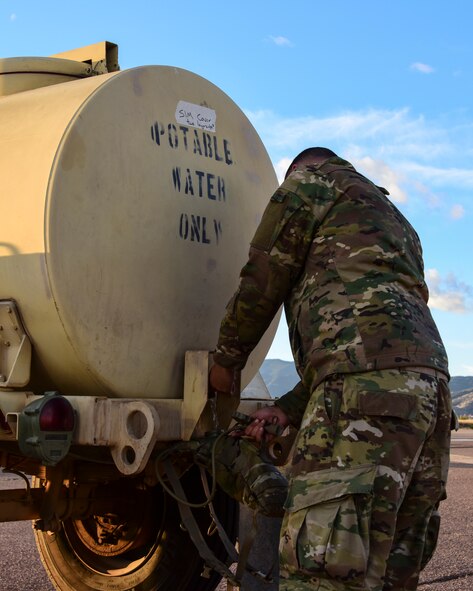 A photo of an airman getting water from water buffalo during an exercise.