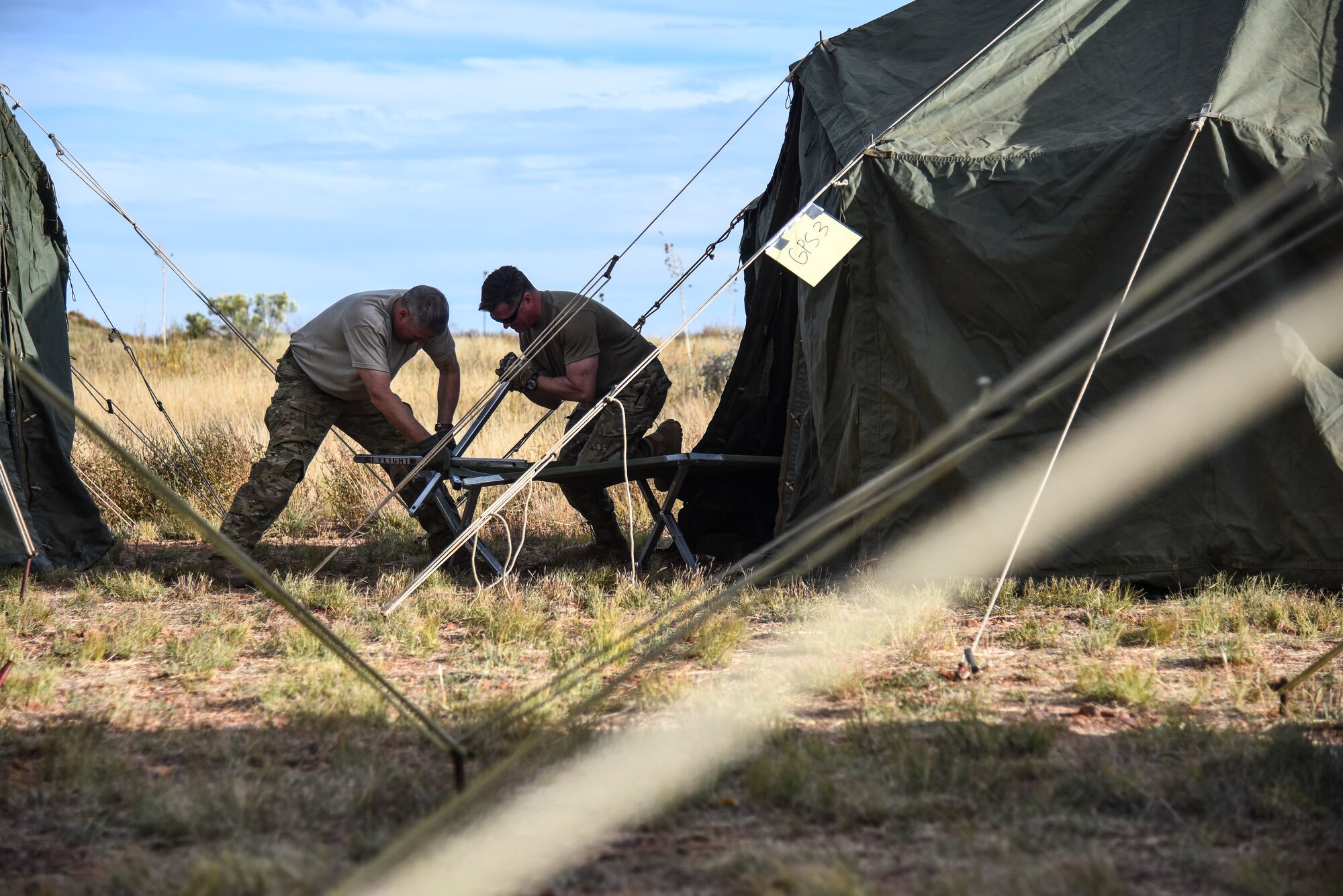 A photo of two airmen assembling tents during an exercise.