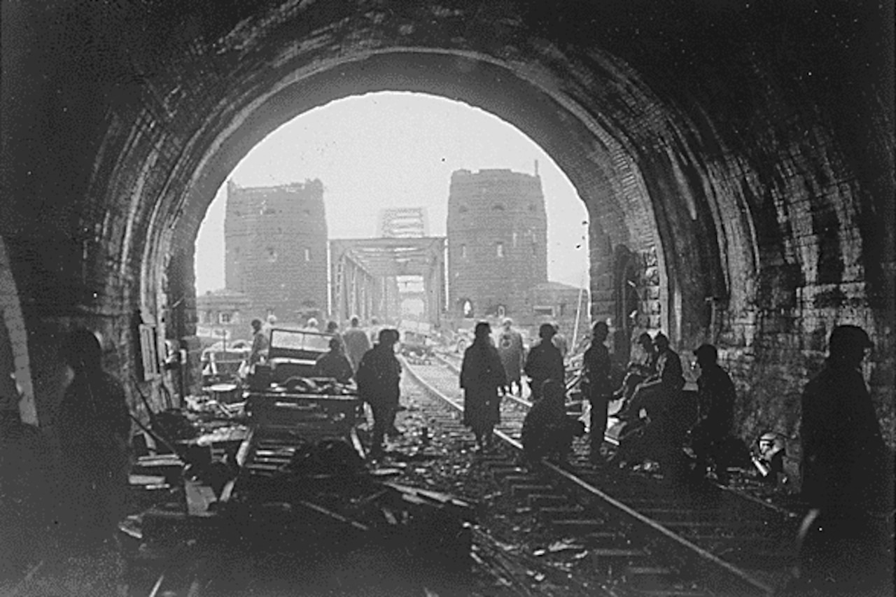 A dozen men stand inside a darkened tunnel.