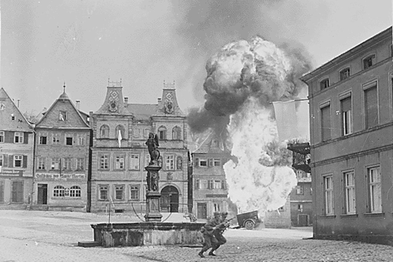 A European city is bombed.  Soldiers run near a statue in the center.