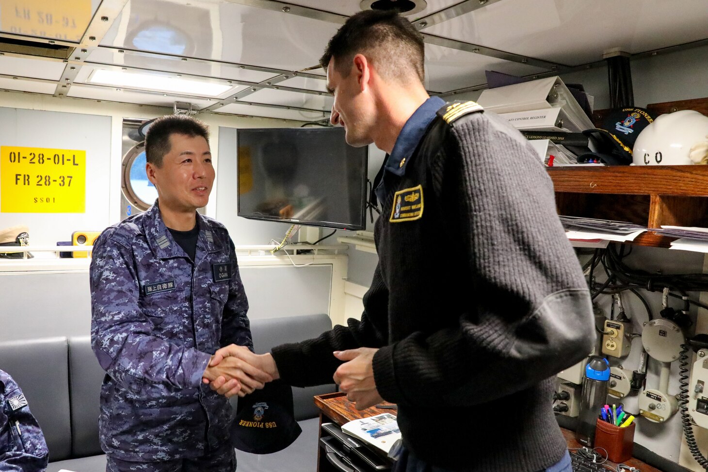 Commanding officer of Avenger-class mine countermeasures ship USS Pioneer (MCM 9)  Lt. Cmdr. Bobby Wayland, right, shakes hands with commanding officer of Japanese mine countermeasure ship JS Hirashima (MSC 601), Lt. Cmdr. Ogawa Tomoyuki.