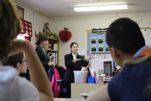 Scientist speaks to classroom of children, uses hand gestures while speaking