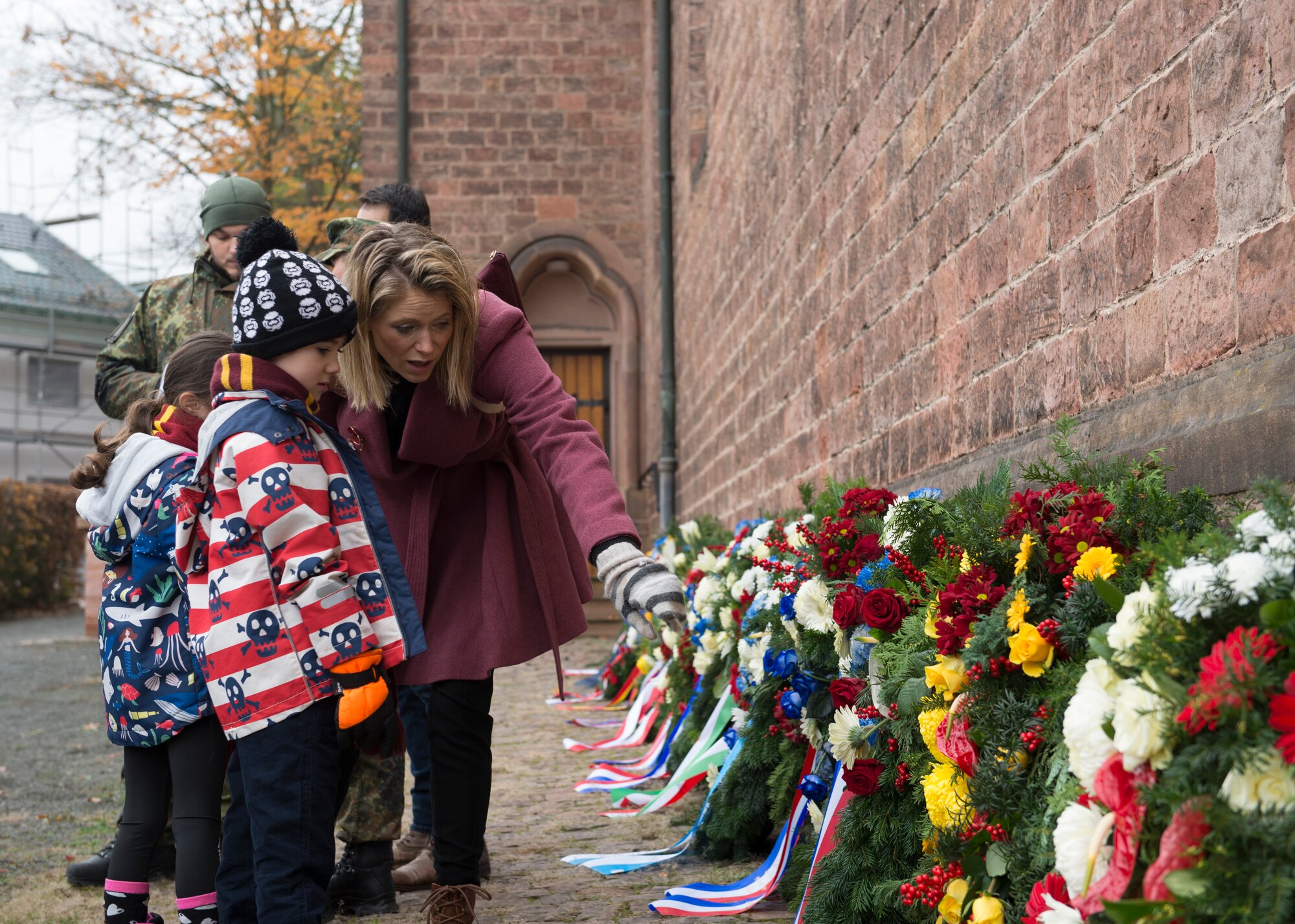 Maxine Antoniou, event attendee, explains the wreaths of various NATO countries to her children at the Ramstein-Miesenbach’s National Day of Mourning Ceremony, Nov. 17, 2019. Antoniou, a former Royal Air Force flight lieutenant, has frequented dedication ceremonies over several years with her children in order to teach them about the past and show the importance of the past sacrifices for freedom and peace.