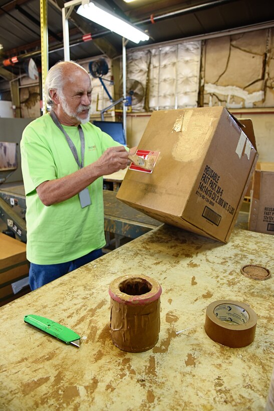 An image of an employee painting on a carboard box to be refurbished and reused for New View Oklahoma.