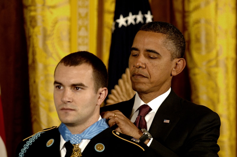 President Barack Obama clasps the Medal of Honor around the neck of Army Staff Sgt. Salvatore Giunta, who solemnly looks forward.