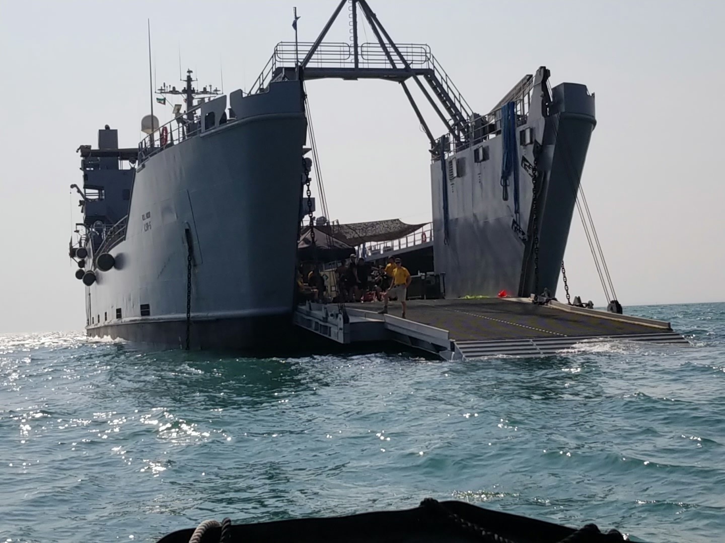 Members of the 511th Engineer Dive Detachment prepare to receive additional divers approaching from the front ramp of the U.S. Army Logistic Support Vessel 5 (LSV-5) near Kuwait Naval Base, Kuwait, Oct. 23, 2019. The vessel at the time was hosting joint training between U.S. Amy 511th Engineer Dive Detachment and members of the Kuwait Fire and rescue Service. (U.S. Army photo by Staff Sgt. Robert Waters)