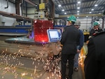 Royal Saudi Naval Forces Eastern Fleet Commander Admiral Fahad Al-Shimrami views MMSC steel cutting in progress at FMM as sparks fly.
