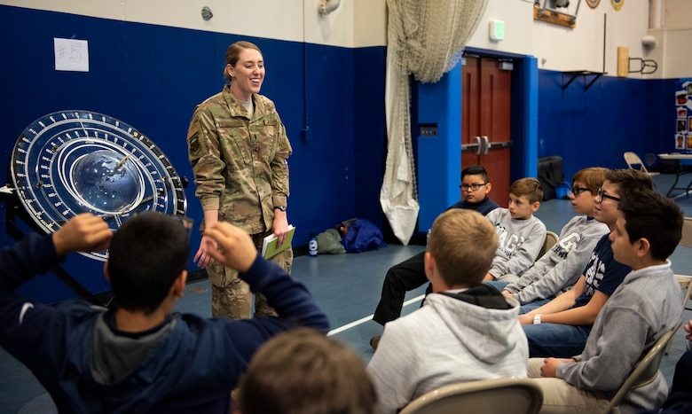First Lt. Rachel West-Lacourrege, 50th Operations Support Squadron chief of 4th Space Operations Squadron intelligence, gives a demonstration during the science, technology, engineering and mathematics day event to James Irwin Charter Academy middle school students Nov. 14, 2019, at the fitness center at Schriever Air Force Base, Colorado. During her briefing, she taught base-level orbital mechanics and Newton’s laws. (U.S. Air Force photo by Airman Amanda Lovelace)