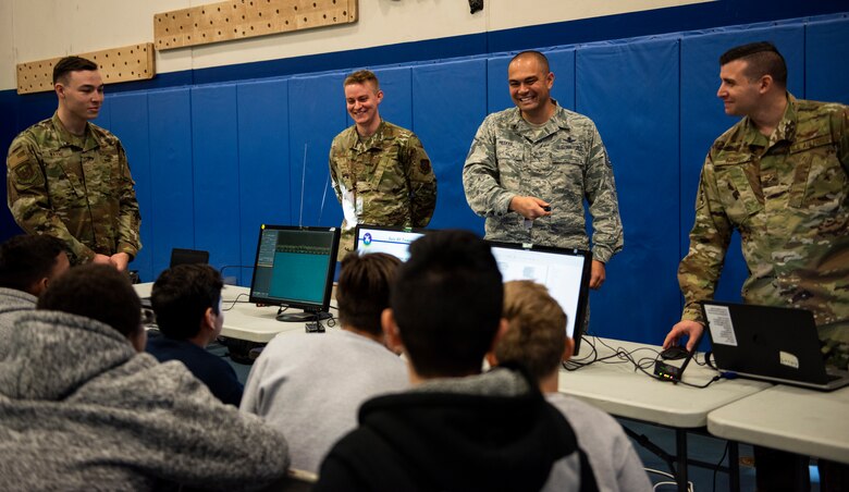 Members of the 50th Operations Support Squadron brief middle schoolers during the science, technology, engineering and mathematics day event Nov. 14, 2019, at the fitness center at Schriever Air Force Base, Colorado. During their brief, they taught the students how radio frequencies can be used to control satellites and send communications. (U.S. Air Force photo by Airman Amanda Lovelace)