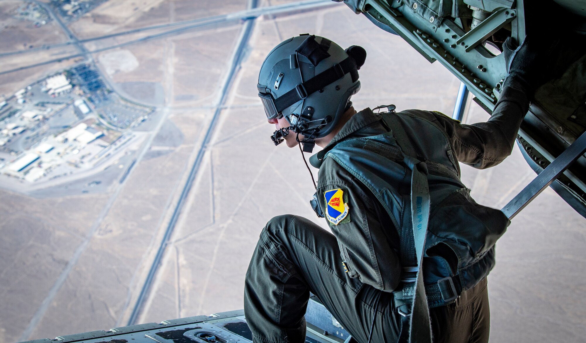 An Airman looks out of the back of an aircraft.
