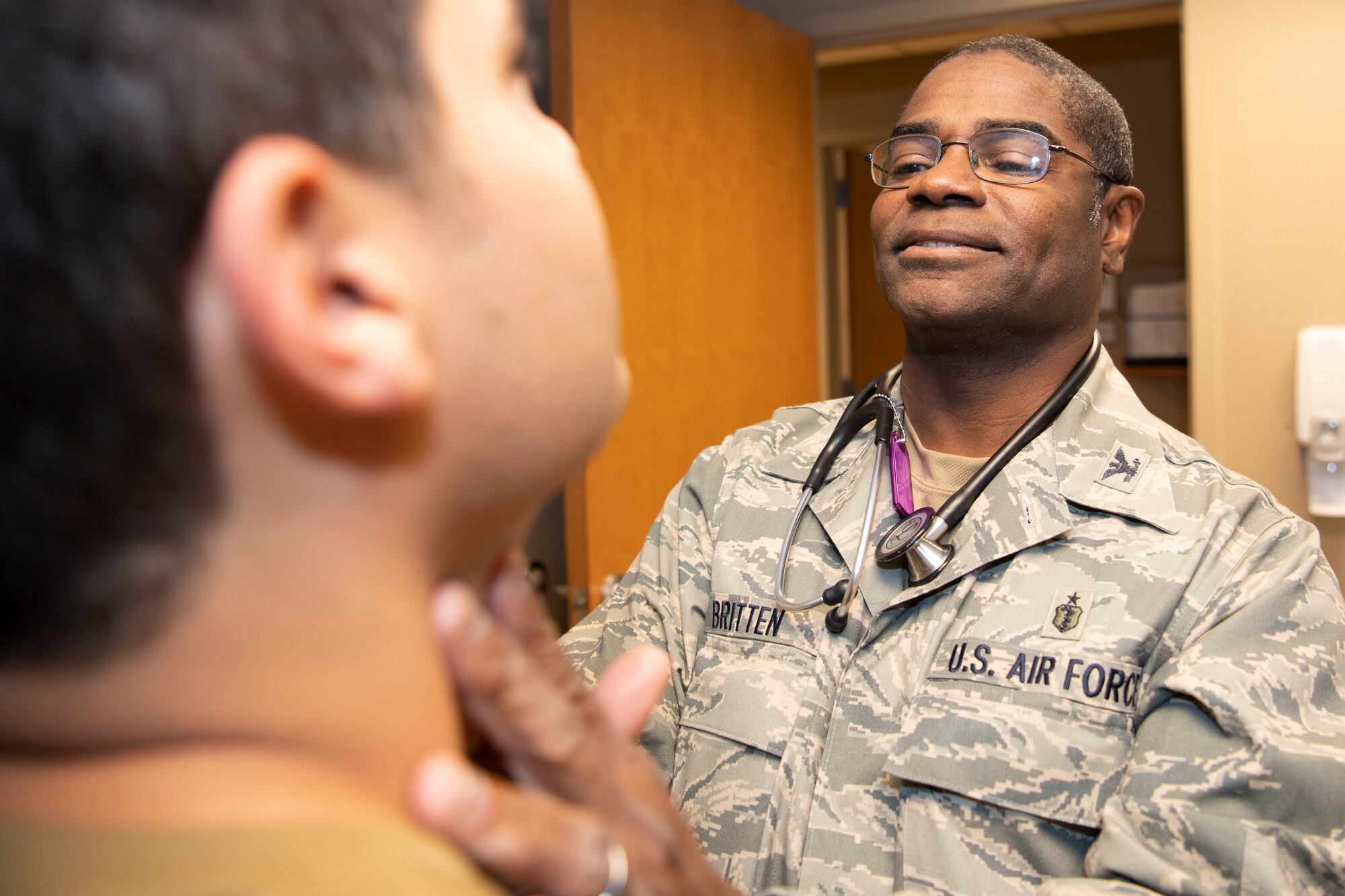 Photo of Col. Dennis Britten performing routine health assessment on patient.