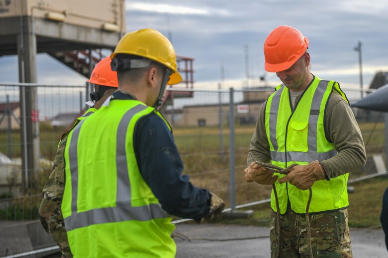 U.S. Airmen from the 31st Maintenance Squadron tie a guide rope at Aviano Air Base, Italy, Nov. 16, 2019. An aircraft lifting sling and guide ropes were used to keep an F-16 Fighting Falcon stable during a disabled crash crane. (U.S. Air Force photo by Airman 1st Class Ericka A. Woolever).