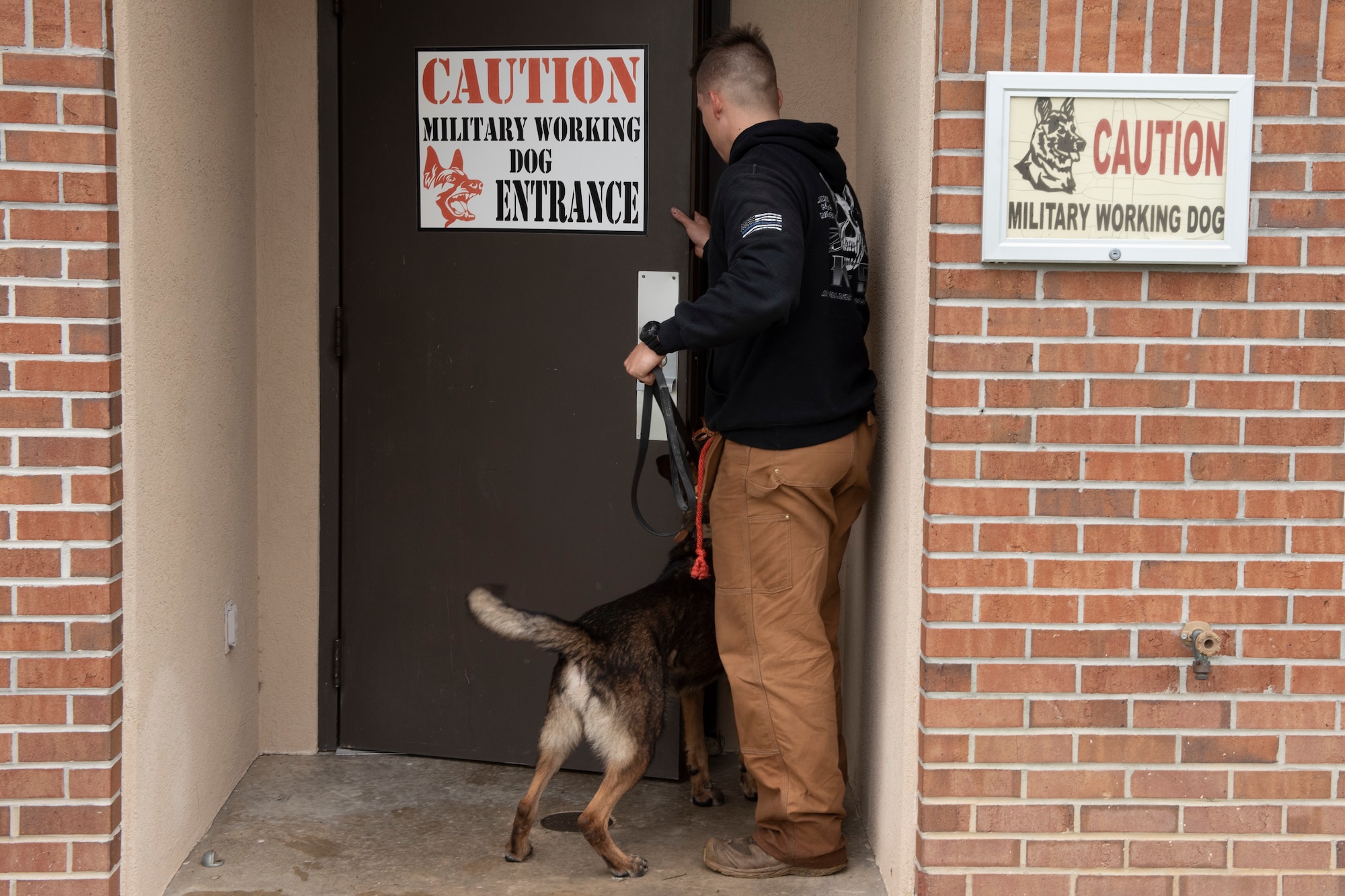 A photo of a military working dog handler escorting a military working dog into a veterinary treatment facility.