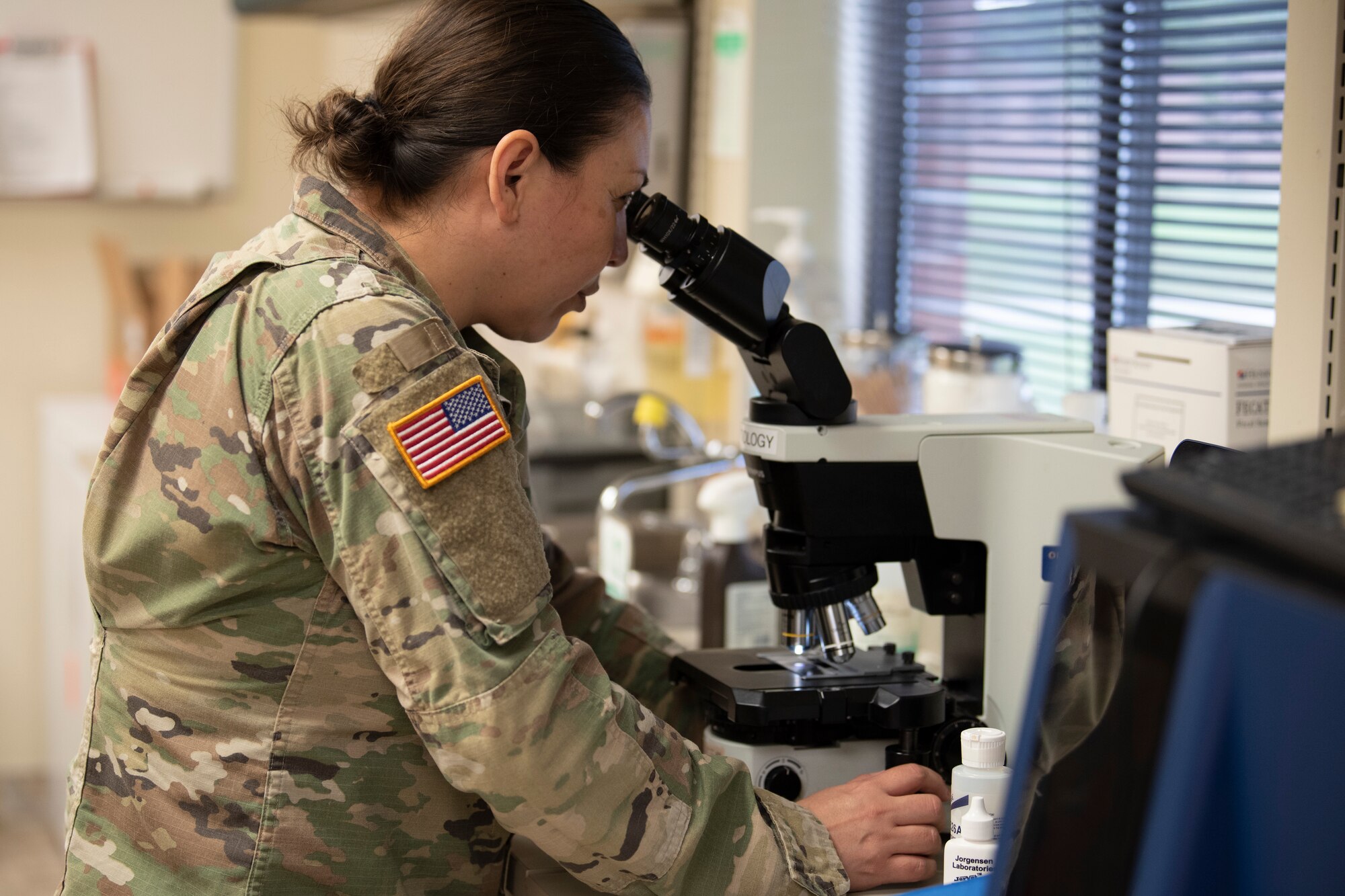A photo of a Soldier examining a sample under a microscope.