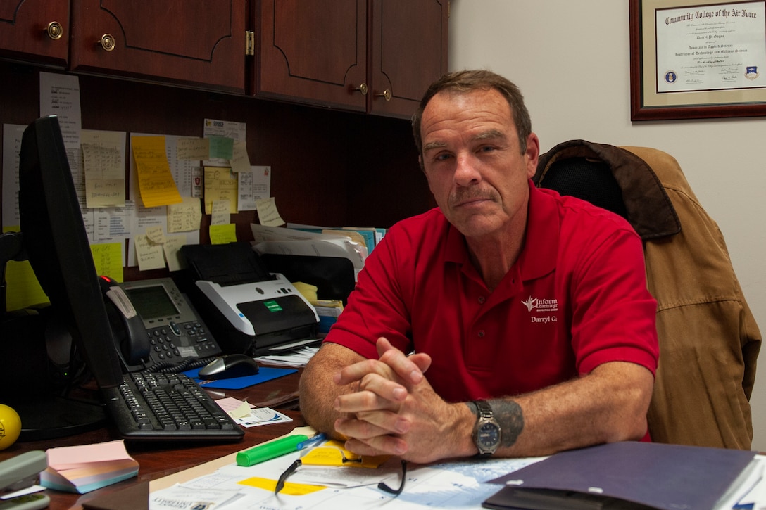 A photo of an education specialist posing for a photo in his office.
