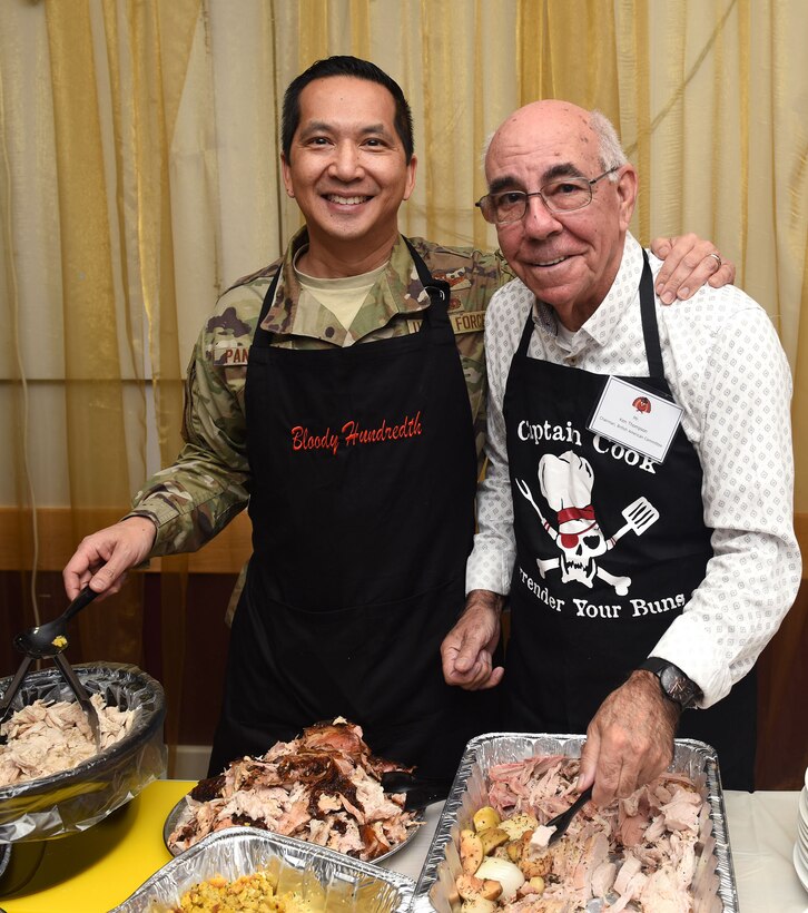 U.S. Air Force Col. Troy Pananon, 100th Air Refueling Wing commander, and Ken Thompson, RAF Mildenhall British-American Committee chairman, pose for a photo while serving Thanksgiving lunch for local senior citizens at the Mildenhall Social Club, Mildenhall, England, Nov. 18, 2019. Base leadership, Airmen and BAC members served the luncheon to build relations and give back to the local community. (U.S. Air Force photo by Karen Abeyasekere)