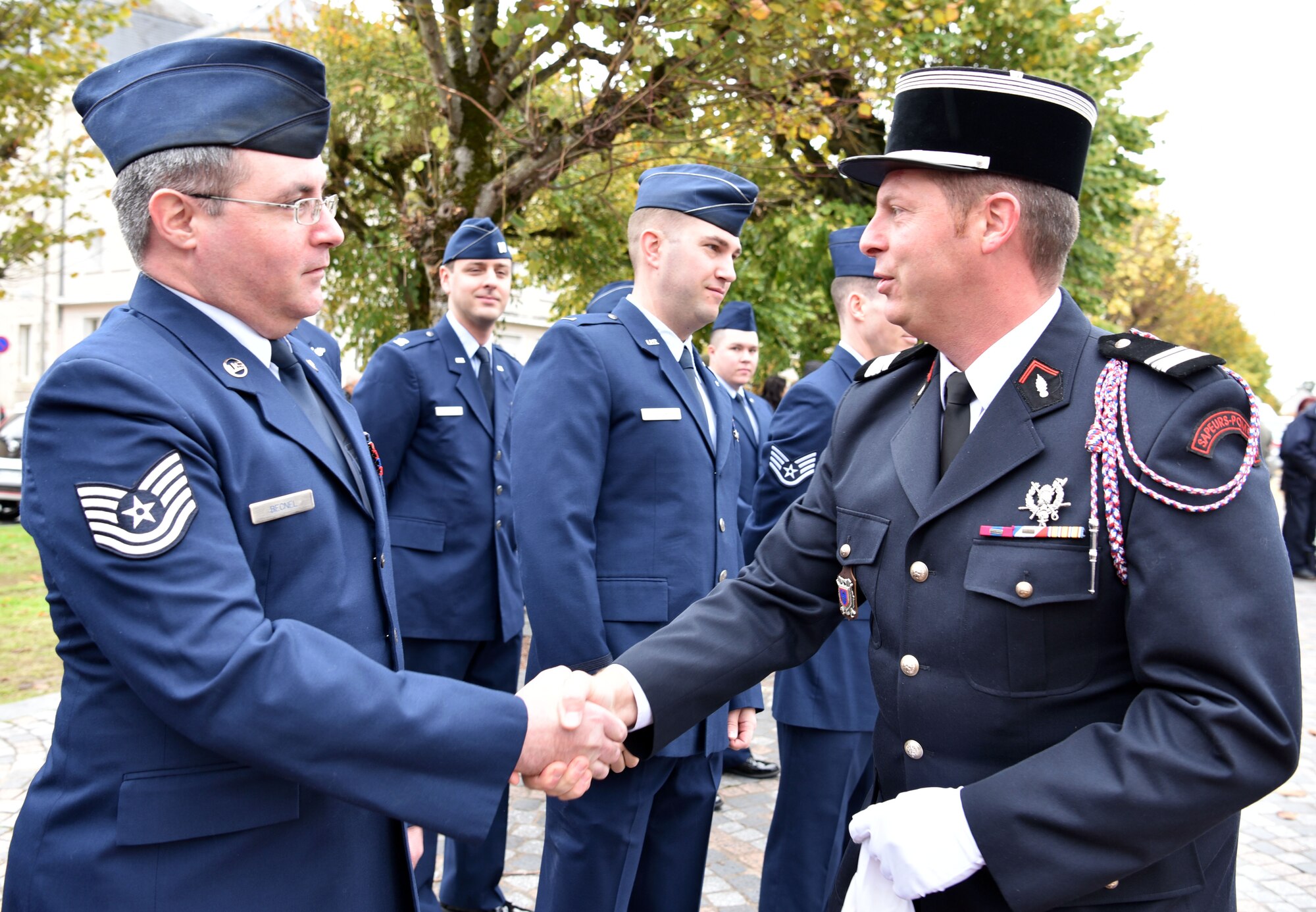 U.S. Air Force Tech. Sgt. Jeremy Becnel, 305th Operations Support Squadron boom instructor, greets a French Fire Services officer prior to taking part in an Armistice Day commemoration Nov. 11, 2019, in Issoudun, France. The Airmen helped commemorate the day and honor fallen Airmen who were stationed at the 3rd Aviation Instruction Center during World War I. (U.S. Air Force photo by Tech. Sgt. Chris Powell)