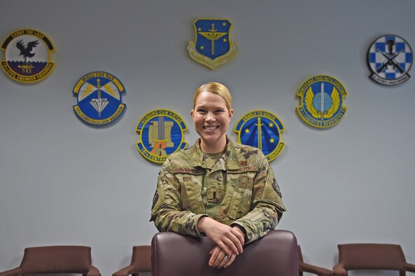 A woman stands in front of a desk.