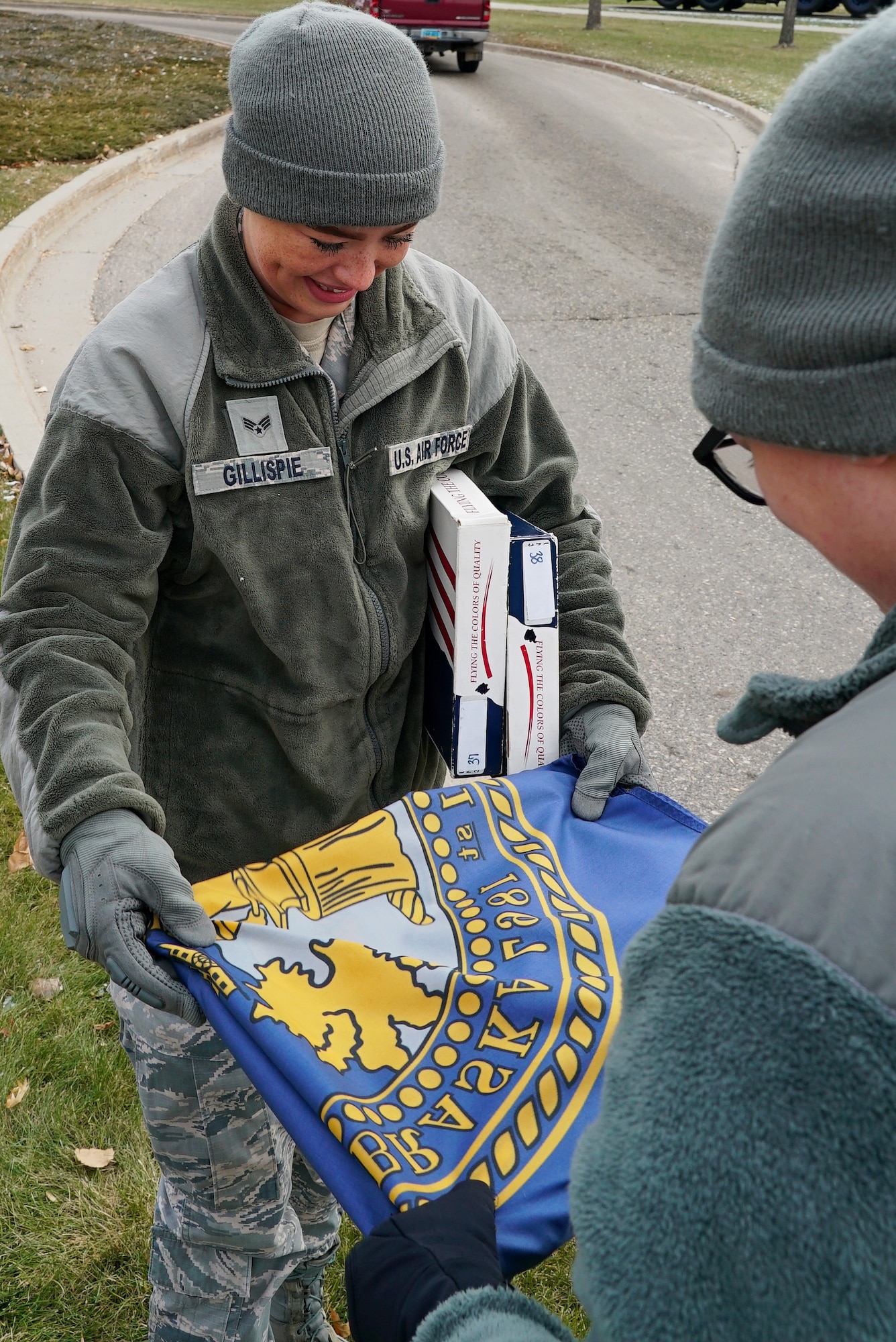 Airman 1st Class Sarah Gillispie and Amn. Shaelynn Ford, 348th Reconnaissance Squadron aviation resource management apprentices, fold the Nebraska flag Nov. 8, 2019, on Grand Forks Air Force Base, North Dakota. Members with the 348 RS replaced the installation’s avenue of state flags with United States flags for Veterans Day, commemorating all servicemembers, past and present. (U.S. Air Force photo by Senior Airman Elora J. Martinez)