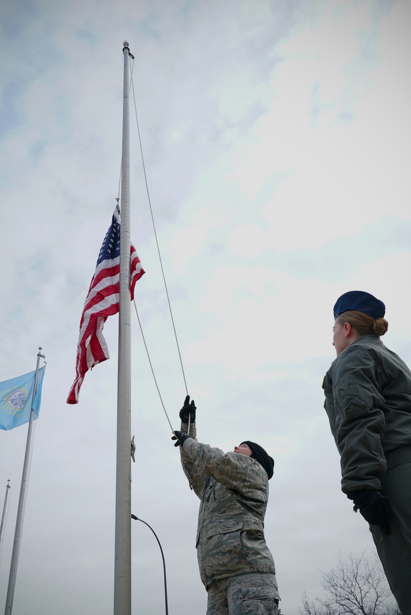 Second Lt. Maria Castle, 348th Reconnaissance Squadron chief of intelligence training, raises a United States flag Nov. 8, 2019, on Grand Forks Air Force Base, North Dakota. Members of the 348 RS volunteered to replace the base’s avenue of state flags with that of the U.S. flag, doing so for Veterans Day to honor all who have served in the U.S. military past and present. (U.S. Air Force photo by Senior Airman Elora J. Martinez)