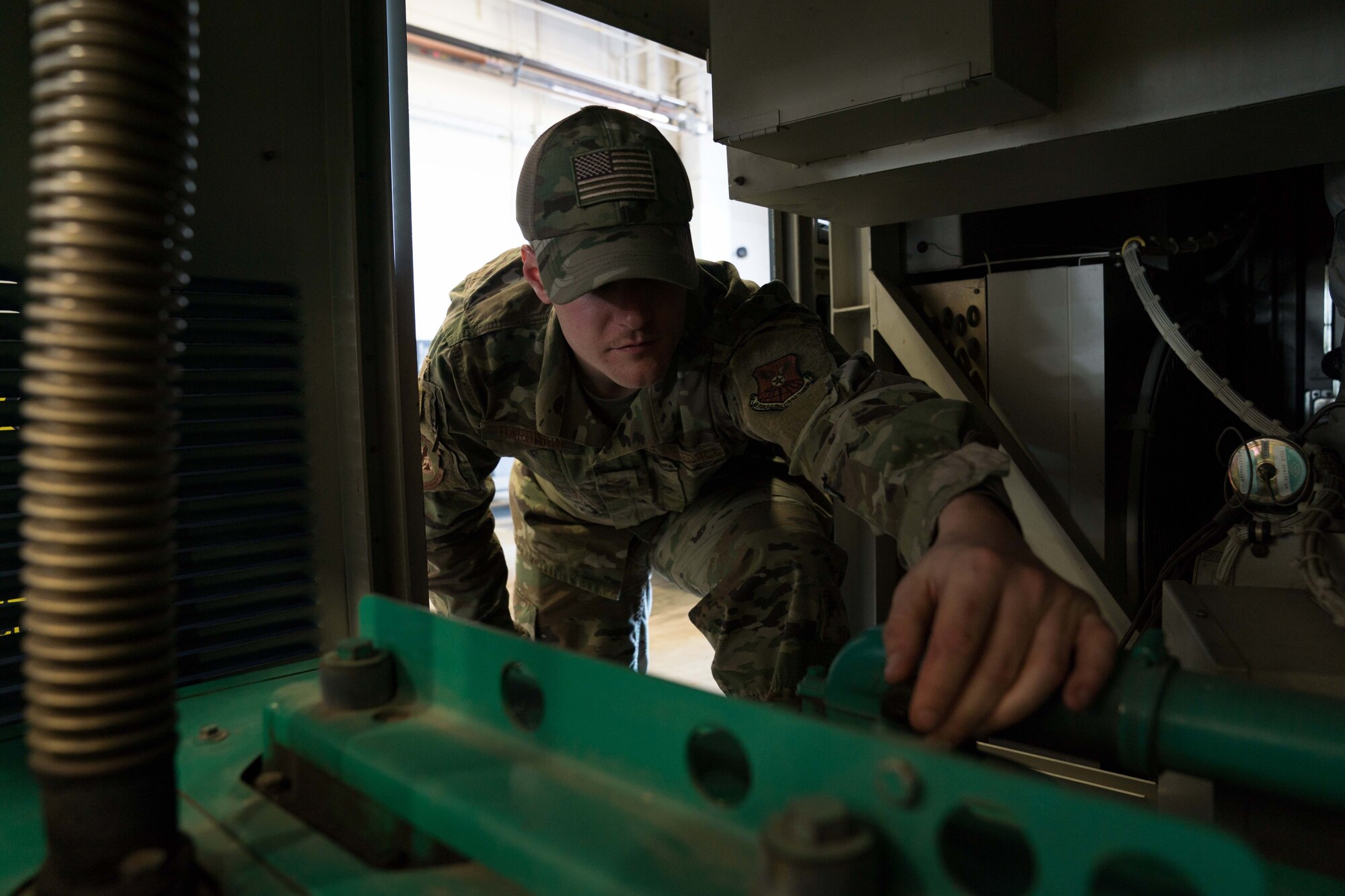 Senior Airman Justin Harrison, 90th Missile Maintenance Squadron, Facility Maintenance Section, support section supervisor, shows how the bump cap can prevent head injuries while performing maintenance on a portable air condition unit on F.E. Warren AFB, Wyoming, Nov. 18, 2019. Tech. Sgt. Haisen Exon, 90 MMXS/FMS, support section NCOIC, teams up with the 90th Missile Wing LaunchWerx agency to bring forward an idea to prevent future head injuries across the wing. (U.S. Air Force photo by Joseph Coslett)