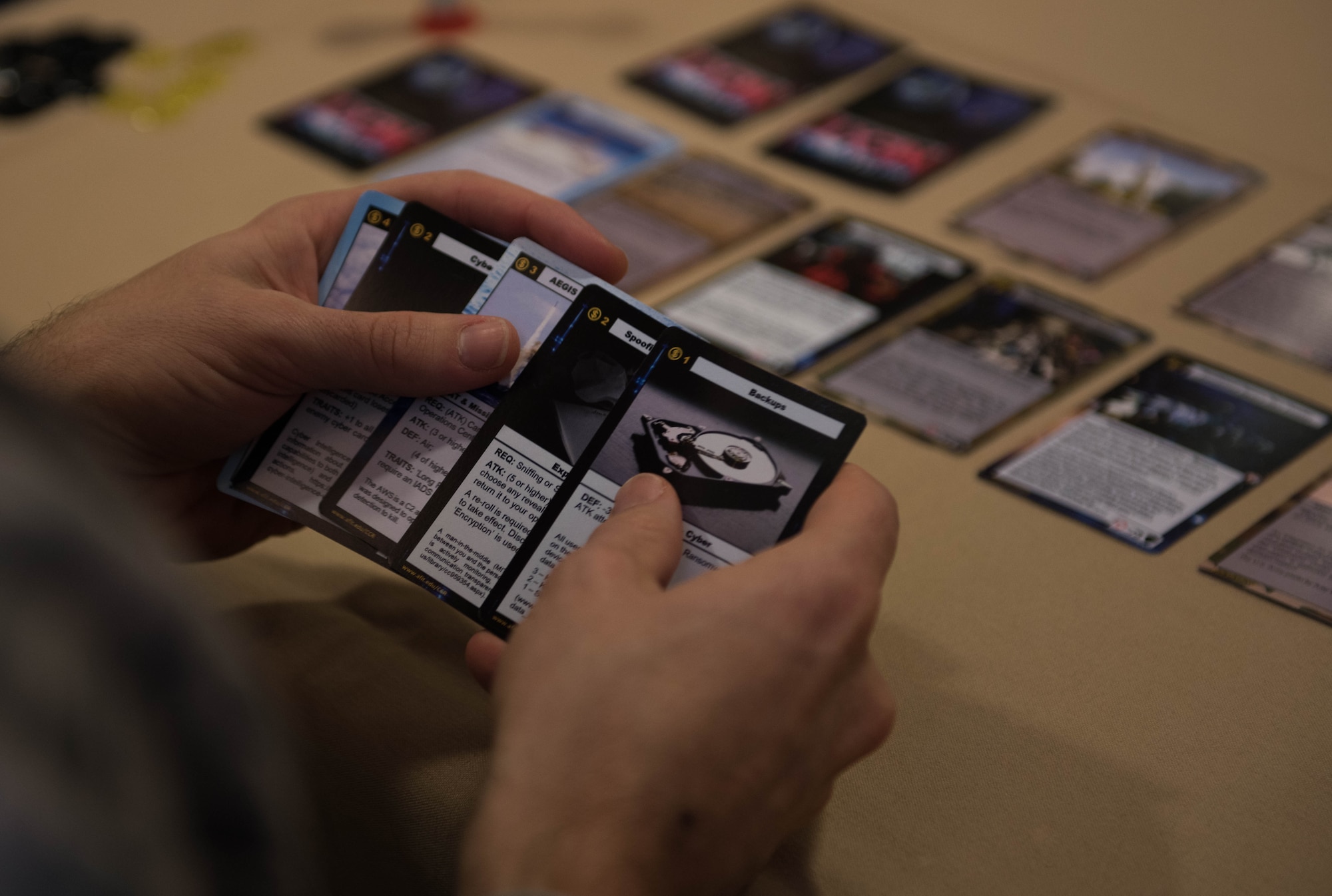 U.S. Air Force Capt. Nathaniel Flack, Department of Electrical and computer engineering student at the Air Force Institute of Technology, holds a deck of Battlespace Next cards at Joint Base Langley-Eustis, Virginia, Nov. 18, 2019. Flack’s game challenges players to think outside the box to solve problems. (U.S. Air Force photo by Airman 1st Class Sarah Dowe)