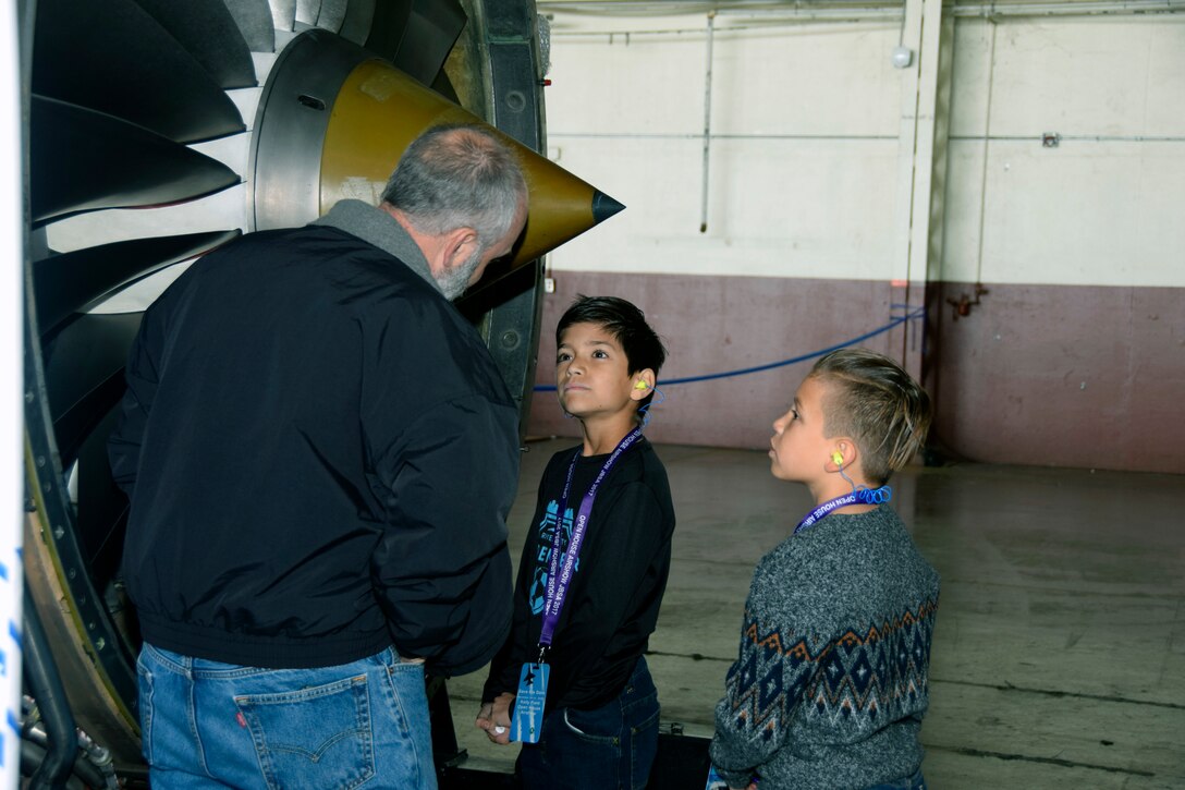 Joshua Shappell and Brodie Alvadel listen to Devin Thompson, a StandardAero employee, talk about engine operation at the Youth Aerospace Expo at Kelly Field, Texas, Nov. 16, 2019.