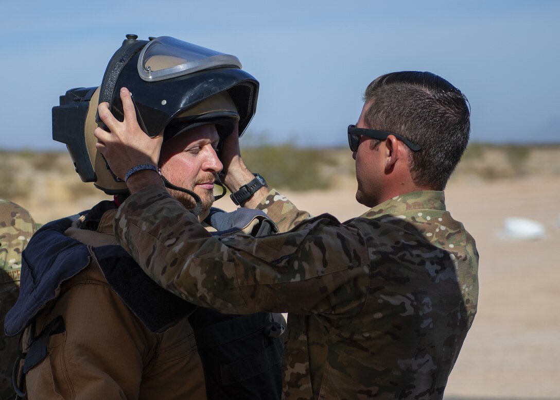 Staff Sgt. David Vincent (right), 56th Civil Engineer Squadron explosive ordnance disposal team chief, fits a Luke Air Force Base Fighter Country Partnership member with an EOD 9 bomb suit during a tour Nov. 14, 2019, at the Barry M. Goldwater Range, Ariz.
