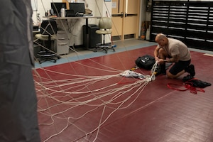 Alaska Air National Guard Tech. Sgt. Eduardo Peguero, 176th Operations Support Squadron aircrew flight equipment technician, checks the lines on a parachute at Joint Base Elmendorf-Richardson, Alaska, Nov. 14, 2019. The AFE Guardian Angel Section supports Alaska’s rescue mission by preparing parachutes and maintaining the equipment needed to deploy pararescuemen as an emergency response.