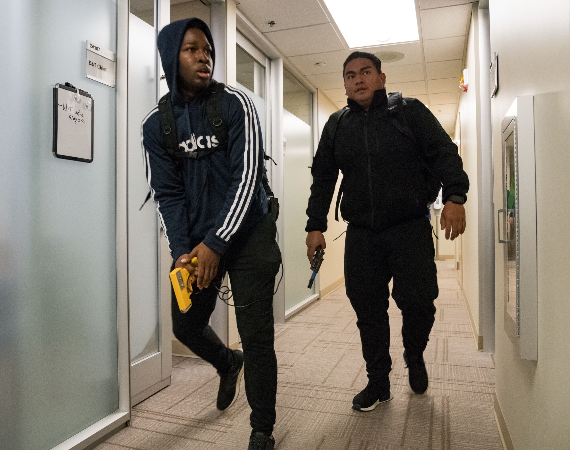 From left, Airman 1st Class Joshua Nichols and Senior Airman Christian Dungca, both 436th Security Forces Squadron response force members, walk around the 436th Medical Group clinic, portraying active shooters during Exercise DORMAR Nov. 12, 2019, at Dover Air Force Base, Del. Base first responders and personnel worked through numerous scenarios,  ensuring the safety of base personnel and assets. (U.S. Air Force photo by Roland Balik)