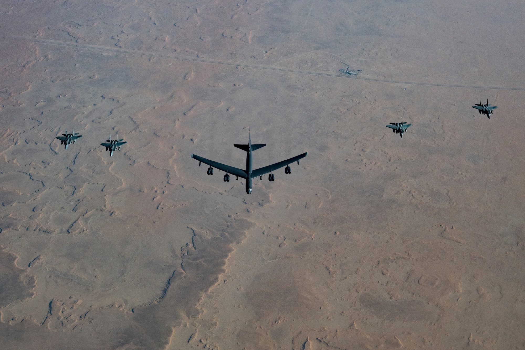A United States Air Force B-52H Stratofortress, accompanied by four Saudi Arabian F-15C Eagles, conducts a low pass over Prince Sultan Air Base, Saudi Arabia, Nov. 1, 2019.