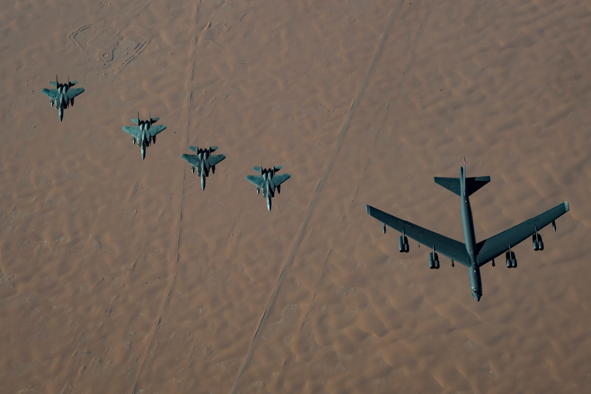 A United States Air Force B-52H Stratofortress, accompanied by four Saudi Arabian F-15C Eagles, conducts a low pass over Prince Sultan Air Base, Saudi Arabia, Nov. 1, 2019. The B-52H, deployed from Barksdale Air Force Base, La., is part of a Bomber Task Force operating out of RAF Fairford, England.