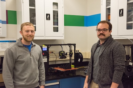 Jacob Aljundi (left) and Ryan Fisher, engineers in the Additive Manufacturing Branch at Naval Surface Warfare Center Carderock Division, stand in front of a 3D printer in Carderock’s Manufacturing, Knowledge and Education Lab on Nov. 15, 2019, in West Bethesda, Md. The two engineers travel to different parts of the world training deployed U.S. Marines how to use 3D printers and the associated software and technology. (U.S. Navy photo by Edvin Hernandez/Released)