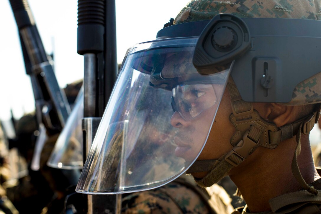 A Marine wears a mask while standing an a line with other Marines.