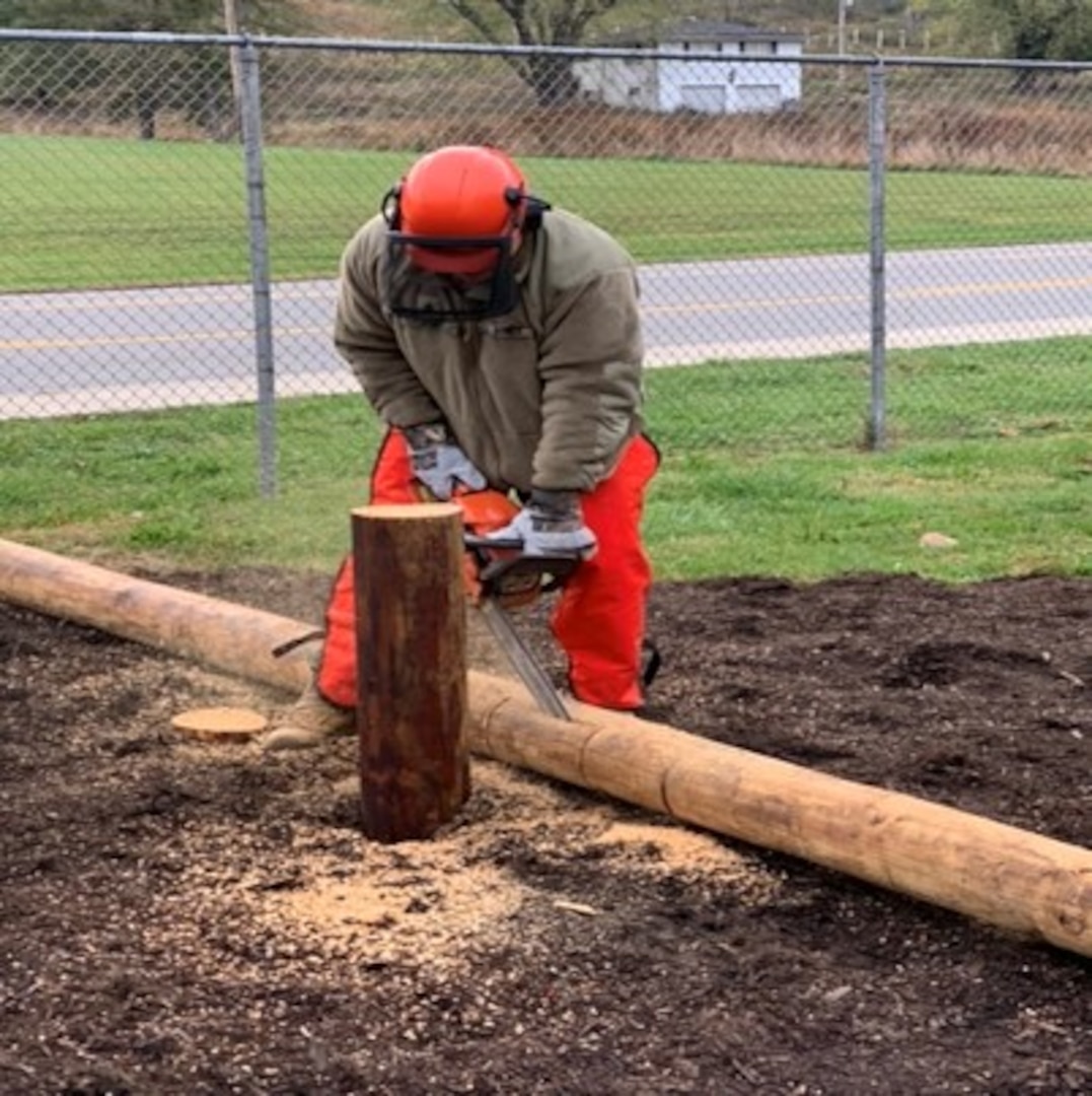 A West Virginia Army National Guard (WVARNG) Soldier assigned to the 1092nd Engineer Battalion cuts a notch into a post in order to complete an obstacle course for the Sissonville High School Marine Corps Junior Reserve Officer Training Corps (MCJROTC). Twelve engineers from the WVANRG completed the obstacle course project in one week as a part of an Innovative Readiness Training (IRT) program. (West Virginia National Guard photo)