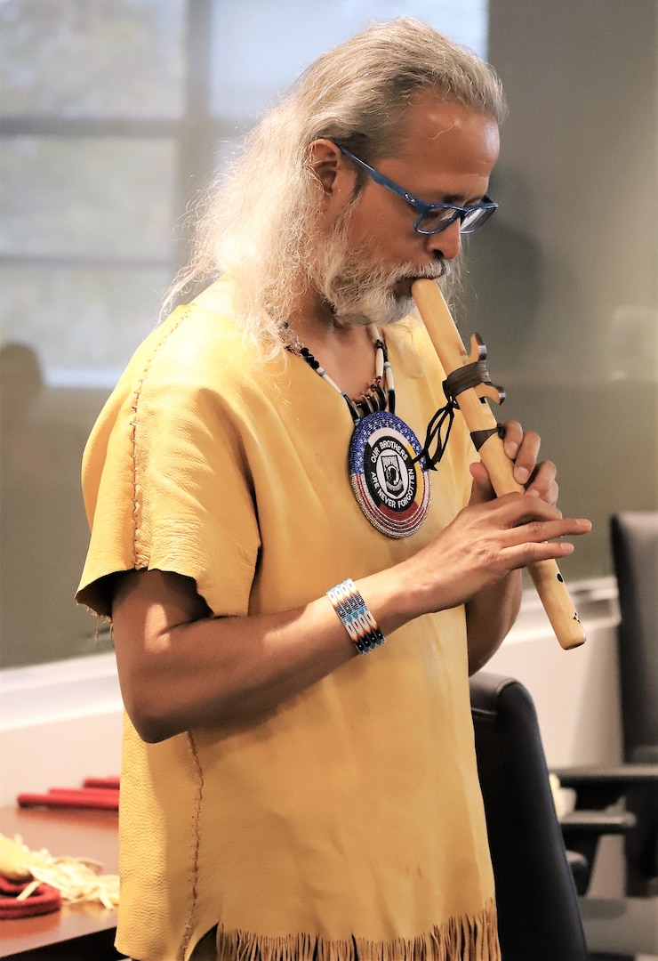 IMAGE: Virginia Beach, Va. (Nov. 12, 2019) – Joe Rubye, a retired Navy chief petty officer and member of the Jicarilla Apache (Tinde) Nation, plays a tribal tune on his flute for Naval Surface Warfare Dahlgren Division - Dam Neck Activity team members during an American Indian Heritage Month celebration in Hopper Hall Auditorium.  (U.S. Navy Photo by George Bieber/Released)
