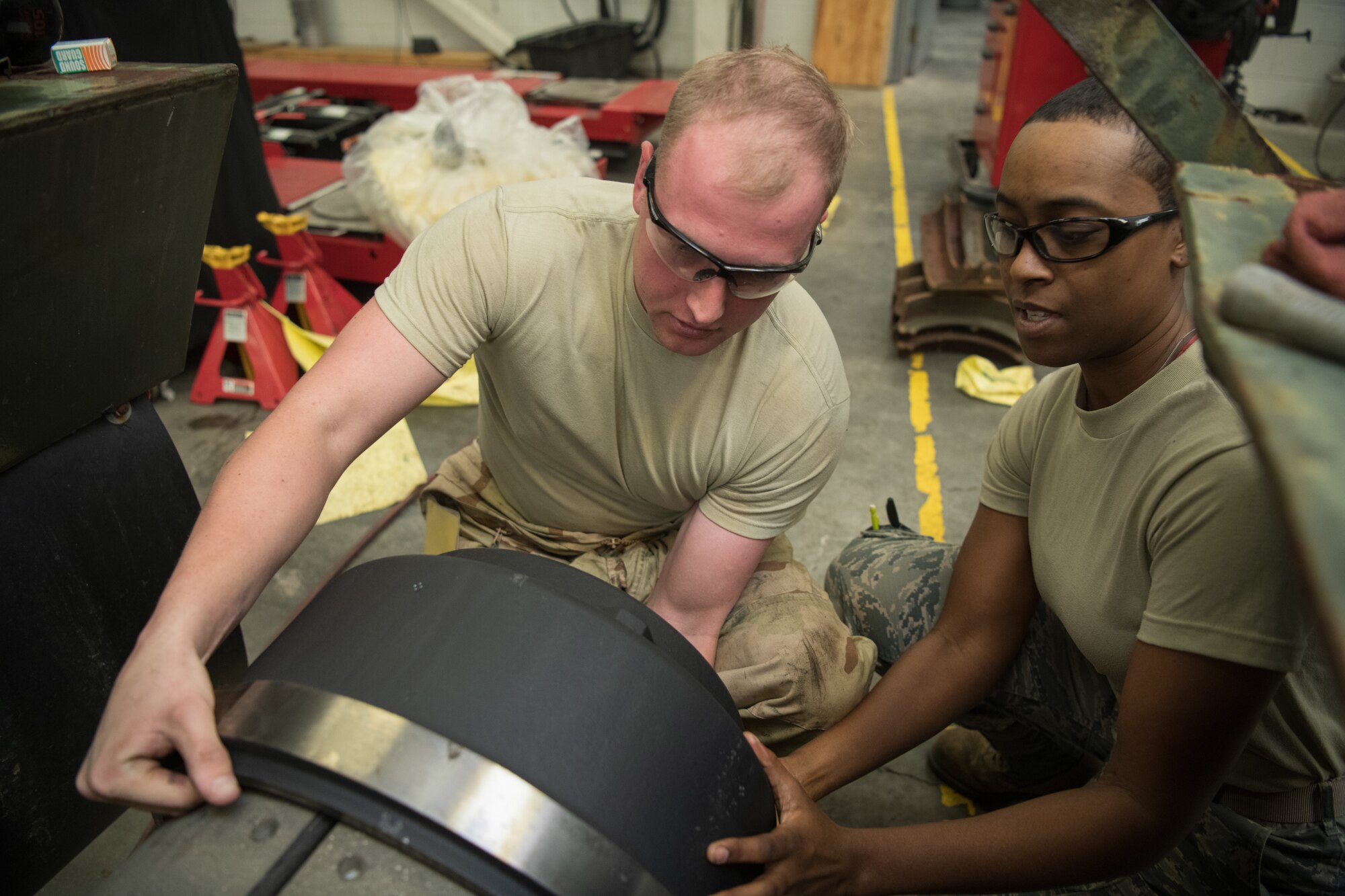 Two Airmen install parts on a trailer