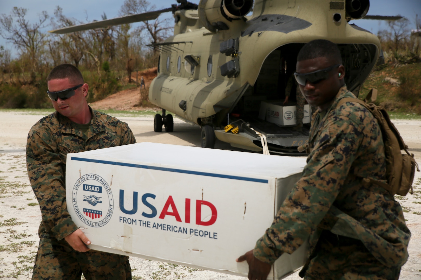 U.S. Marine Lance Cpl. Alex Hurtado and Gunnery Sgt. Damian Henry, a heavy equipment operator and the engineer chief with Special Purpose Marine Air-Ground Task Force - Southern Command, deployed in support of Joint Task Force Matthew, off load supplies for locals affected by Hurricane Matthew at Jeremie, Haiti, Oct. 9, 2016.