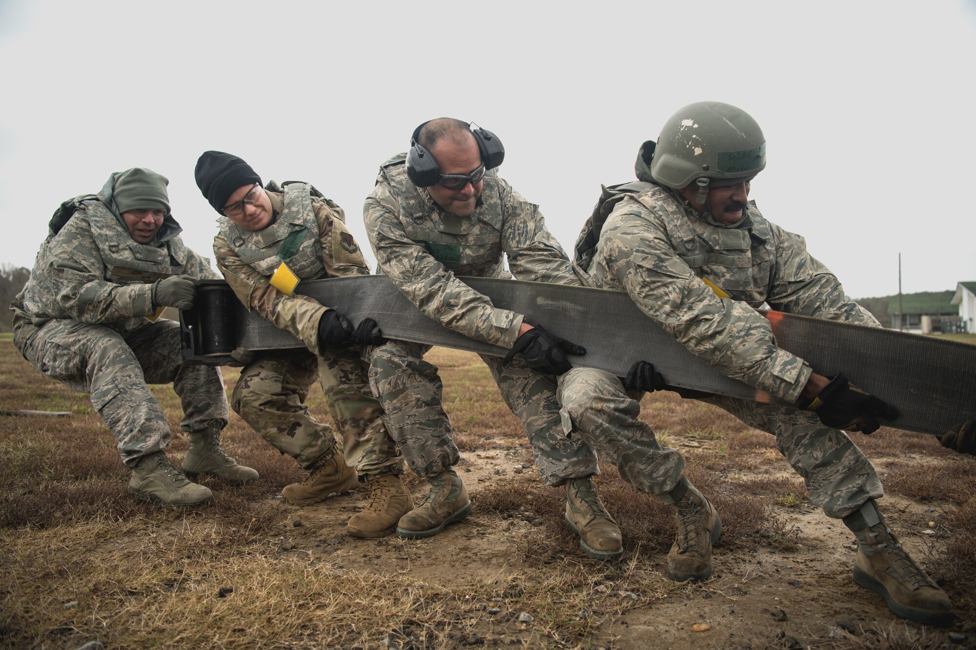 Four Airmen pull on an arresting cable belt