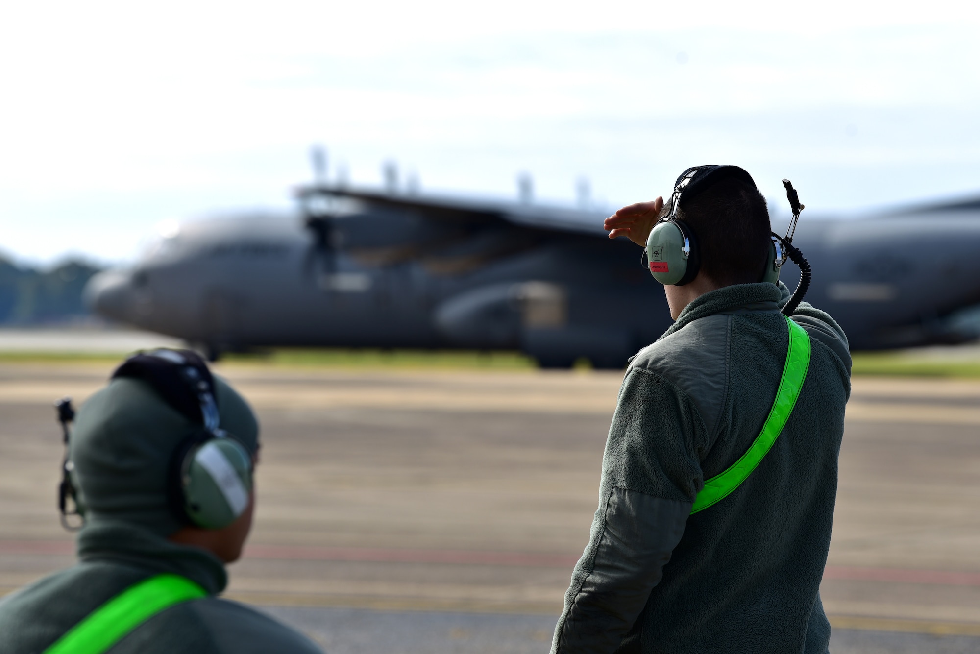 Personnel in uniform operate in and around an aircraft on an airfield