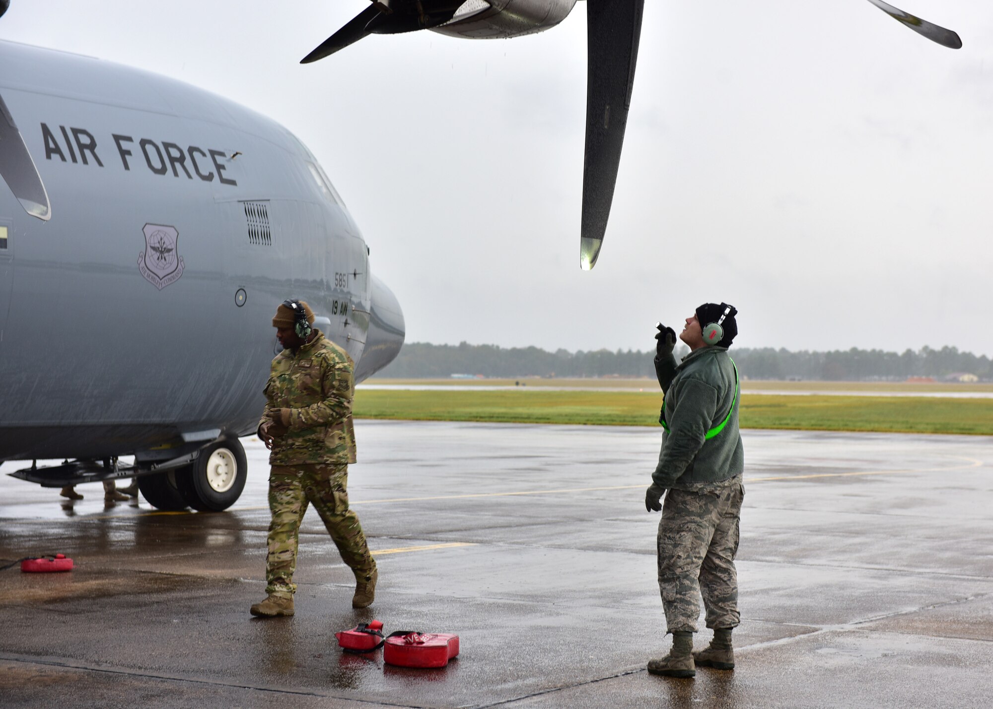 Personnel in uniform operate in and around an aircraft on an airfield